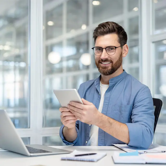 Man holding a mobile device and a laptop in front