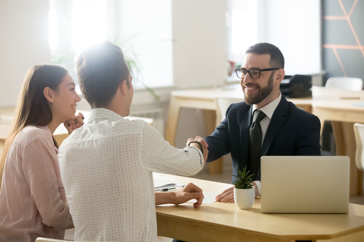 Smiling lawyer, Real Estate Agent or financial advisor handshaking young couple thanking for advice, insurance broker or bank worker and millennial customers shake hands making deal, investment or taking loan